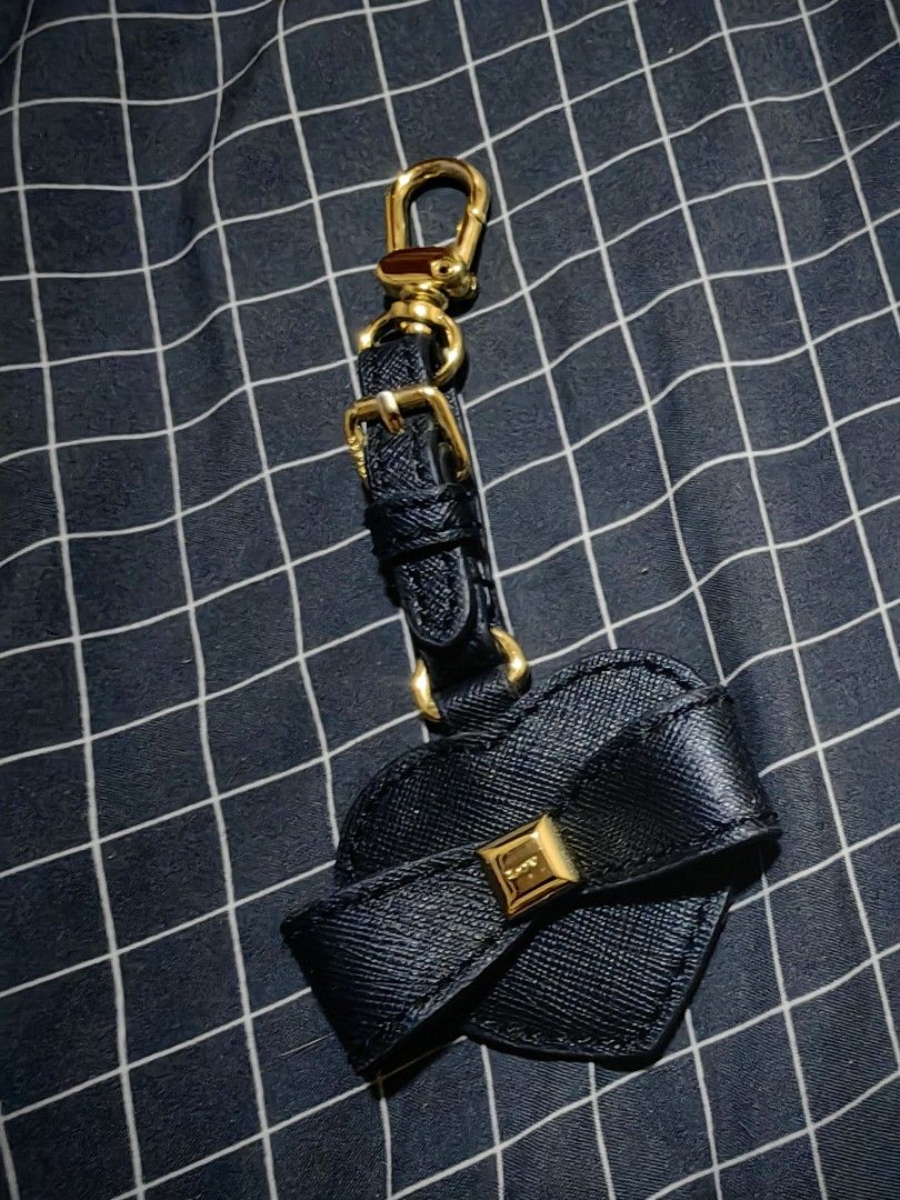 LOVCAT Paris Black Heart Bow Bag Charm (Category: Charms) located in Davao. Submitted by thefrugalshop (Listing ID 1466086926, Image 1). Description: - Brand: LOVCAT PARIS - Design: Navy blue textured leather heart charm with a matching bow and gold square accent - Hardware: Gold swivel clasp and adjustable strap buckle at the top - Details: Debossed logo on the back - Condition: Good, with slight fraying along the left edge of the heart - Perfec