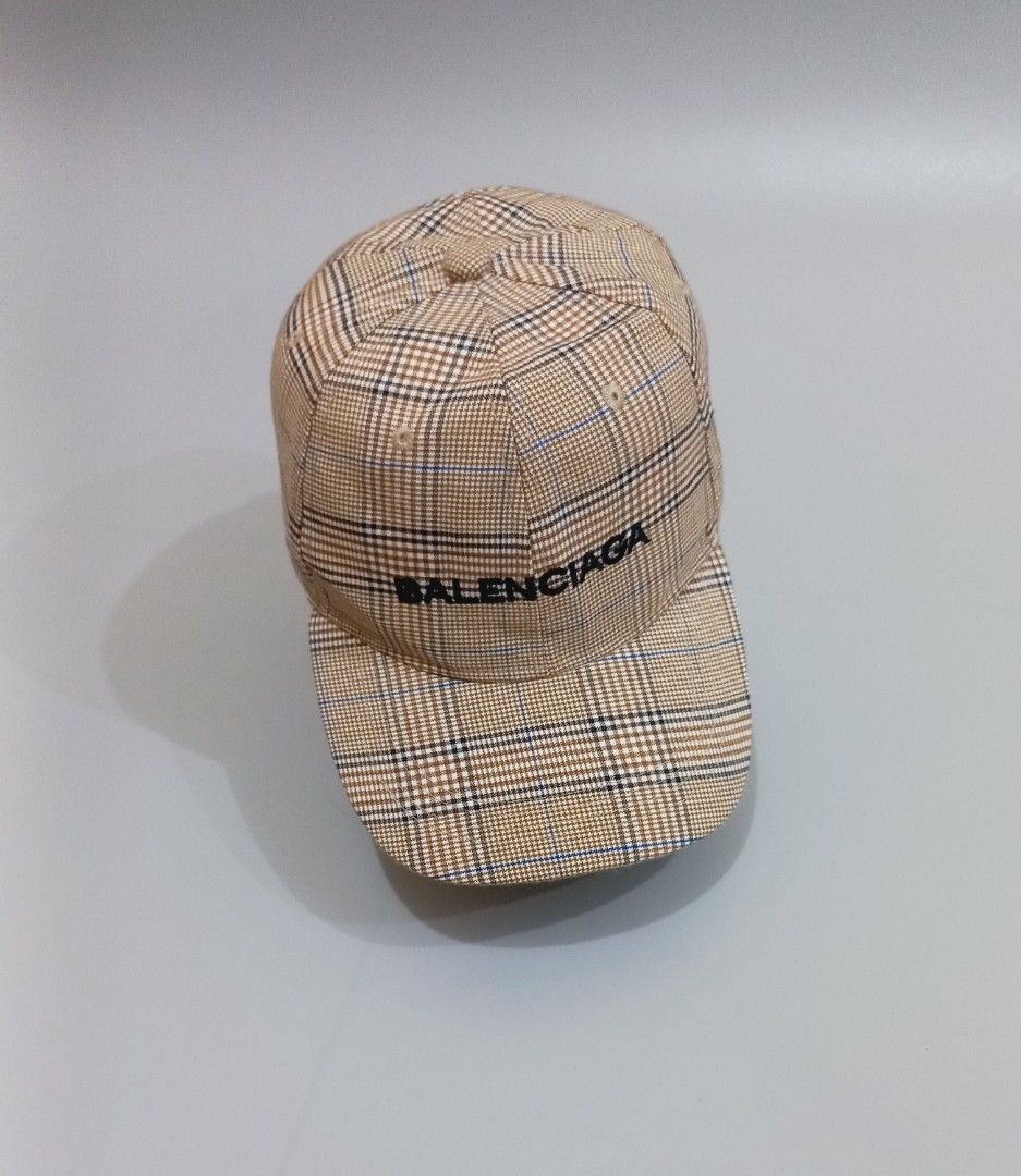 Balenciaga Plaid Check Baseball Cap (Category: Caps & Hats) located in Cebu City. Submitted by MrLiks_123 (Listing ID 1466107593, Image 2). Description: Balenciaga Baseball cap in a stylish beige plaid check pattern - Details: Contrast black embroidered Balenciaga logo on the front - Hardware: Silver-tone metal buckle stamped with the letter 'B' on the adjustable back strap - Construction: Clean fabric with structured panels and top eyelets for b
