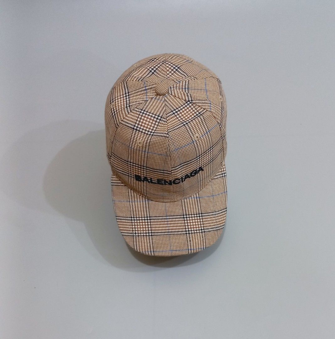 Balenciaga Plaid Check Baseball Cap (Category: Caps & Hats) located in Cebu City. Submitted by MrLiks_123 (Listing ID 1466107593, Image 3). Description: Balenciaga Baseball cap in a stylish beige plaid check pattern - Details: Contrast black embroidered Balenciaga logo on the front - Hardware: Silver-tone metal buckle stamped with the letter 'B' on the adjustable back strap - Construction: Clean fabric with structured panels and top eyelets for b