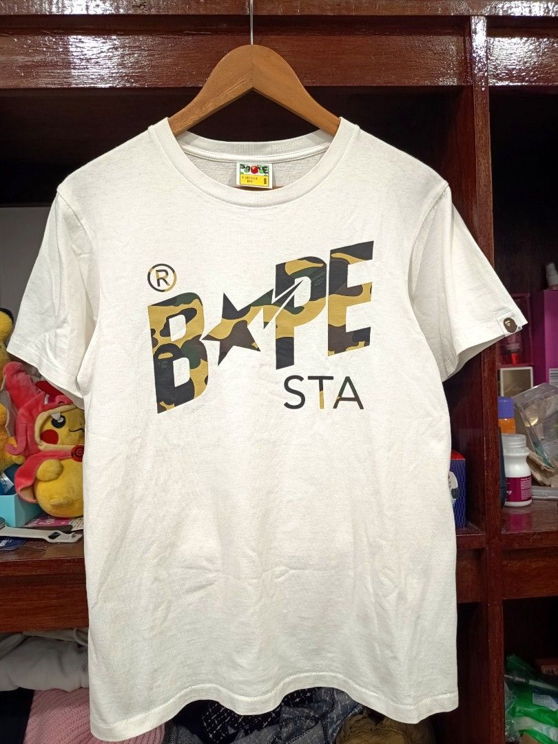 Bape Sta First Camo Script T Shirt (Category: Tshirts & Polo Shirts ) located in Dagupan City. Submitted by plugofallthreads (Listing ID 1466121956, Image 1). Description: Bape Sta First Camo Script T Shirt Size: Men's Small Length: 25 inches Width: 18 inches Authentic. In very good condition. 10/10 print. 9/10 cloth. Price: Php 1,500 plus sf DM TO PURCHASE.