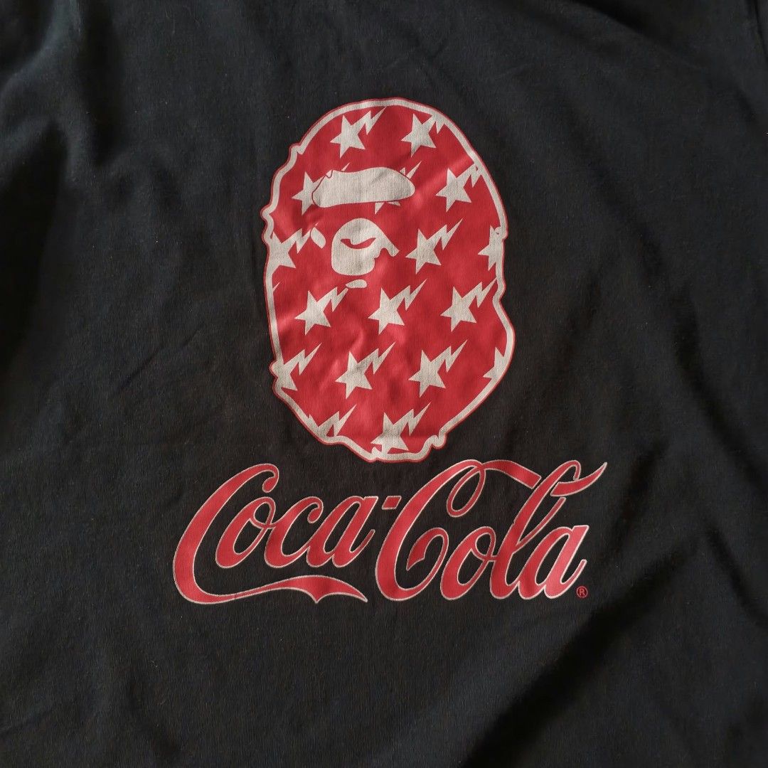 BAPE x Coca-Cola Black T-shirt (Category: Shirts) located in Paranaque City. Submitted by thriftine5 (Listing ID 1466009543, Image 2). Description: - Authentic BAPE x Coca-Cola collaboration t-shirt - Color: Classic Black - Material: Comfortable 100% Cotton - Front design: Iconic ape head filled with red star and lightning bolt graphics, plus Coca-Cola branding and woven hem tag - Back design: 'the Real Thing!' and 'A Bathing Ape' lettering - Det