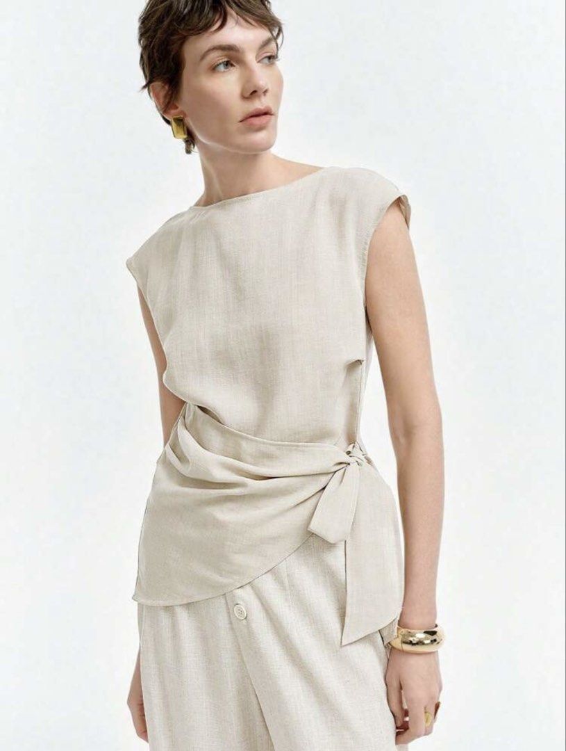 Beige Linen Wrap Blouse Sleeveless Top (Category: Blouses) located in Cebu City. Submitted by wearhousebyhya (Listing ID 1466023228, Image 1). Description: - Color: Neutral beige - Material: Lightweight and breathable linen - Design: Sleeveless with a structured boat neckline - Detail: Wrap-around front panel with a side bow - Hem: Trendy asymmetrical cut - Fit: Versatile and perfect for warm weather.