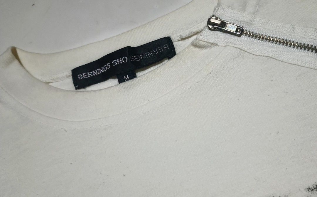 Bernings-Sho Graphic Longsleeve (Category: Longsleeves) located in Calabanga. Submitted by bekneegear (Listing ID 1466123482, Image 3). Description: - Brand: Bernings-Sho - Color: Off-white - Size: Medium (Tag attached) - Design: Large graphic print with 'BERNINGS-SHO BEHAVIOR' text - Details: Diagonal zipper near the collar, brand labels on neck and sleeve hem - Style: Unique grunge streetwear.