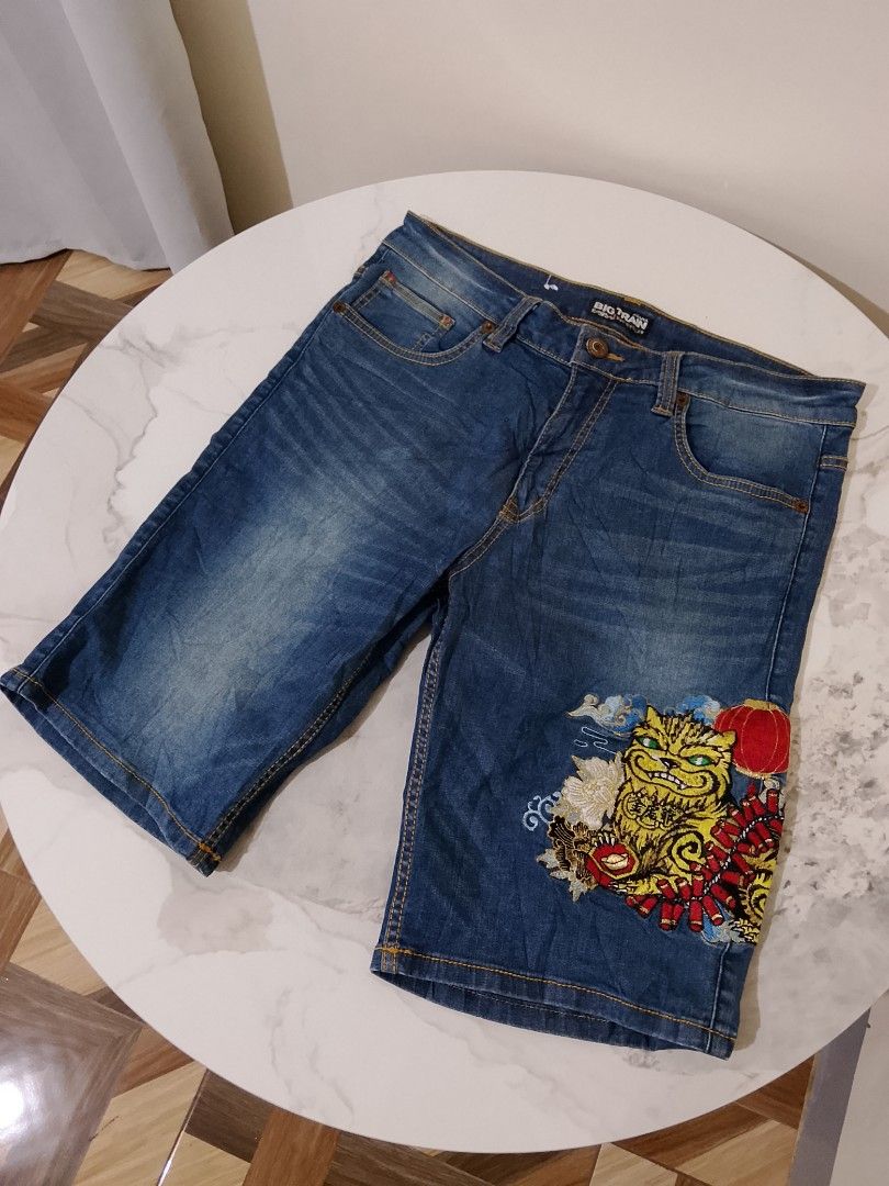 Big Train Embroidered Tiger Denim Shorts (Category: Shorts) located in Manila. Submitted by keencrystal.595c28 (Listing ID 1466022633, Image 1). Description: - Brand: Big Train - Wash: Classic blue - Design: Unique tiger, firecracker, and lantern embroidery on the left leg - Details: Standard five-pocket styling, zip fly, button closure, and contrast yellow stitching - Style: Asian-inspired streetwear piece.