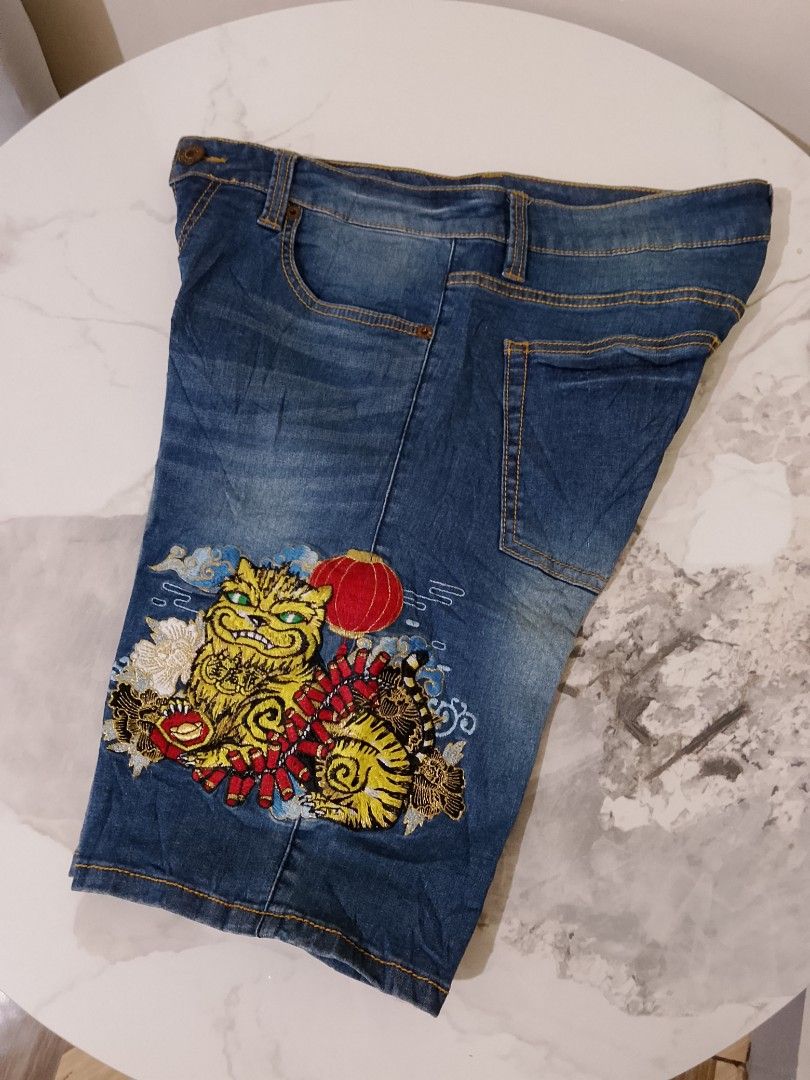 Big Train Embroidered Tiger Denim Shorts (Category: Shorts) located in Manila. Submitted by keencrystal.595c28 (Listing ID 1466022633, Image 2). Description: - Brand: Big Train - Wash: Classic blue - Design: Unique tiger, firecracker, and lantern embroidery on the left leg - Details: Standard five-pocket styling, zip fly, button closure, and contrast yellow stitching - Style: Asian-inspired streetwear piece.