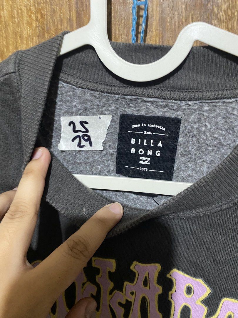 Billabong Graphic Wave Sweatshirt Grey (Category: Coats, Jackets and Outerwear) located in Imus. Submitted by frootiloots4103 (Listing ID 1466002258, Image 2). Description: - Brand: Billabong - Color: Dark grey - Size: 25x29 - Design: Bold retro wave graphic with pink and yellow lettering and 1973 text - Style: Crew neck with soft fleece lining - Condition: Good, features a small handwritten tag near the inner collar OPEN FOR NEGO (best if aspack