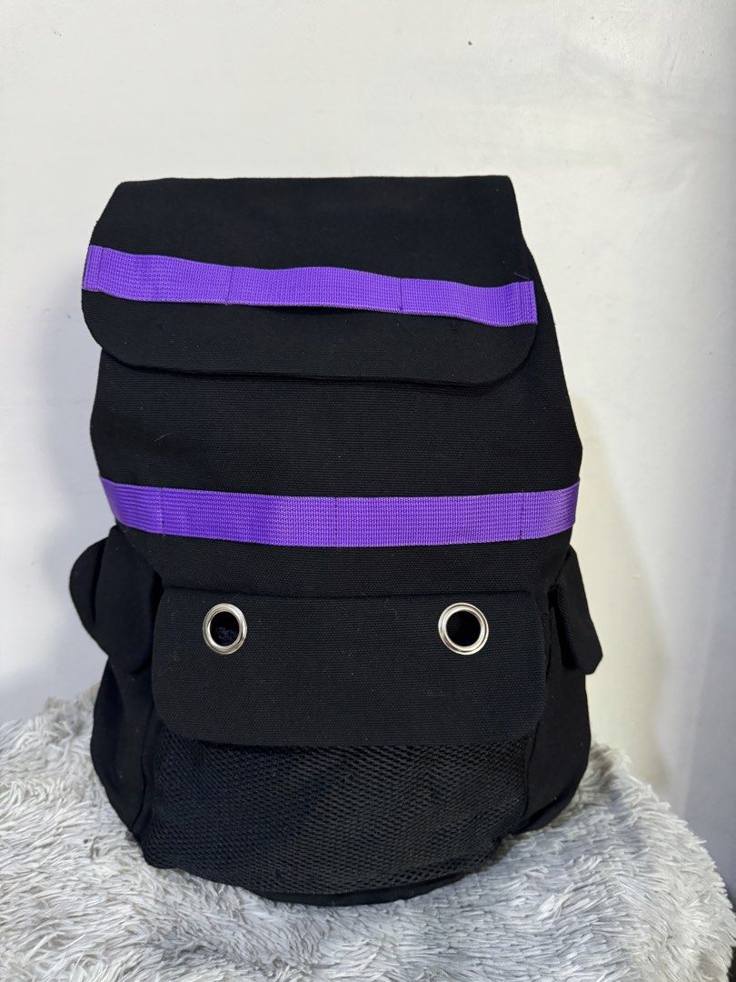 Black Canvas Backpack with Colorful Striped Accent Straps (Category: Backpacks) located in Urdaneta. Submitted by kathleenja24136 (Listing ID 1465957950, Image 1). Description: Solid black canvas backpack with vibrant striped straps across the top flap and front body. Main flap closure with buckle straps underneath. Front pocket features two metal grommet eyelets and a mesh lower section. Adjustable shoulder straps on the back. Sturdy fabric cons