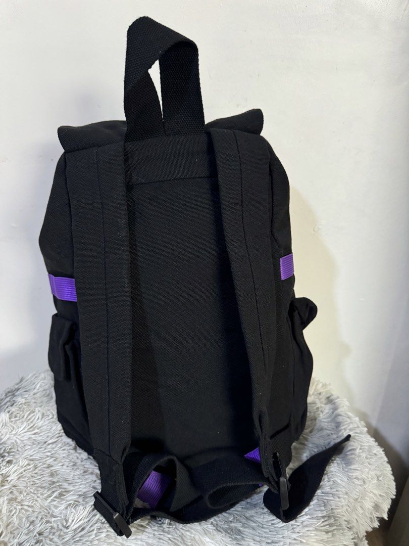 Black Canvas Backpack with Colorful Striped Accent Straps (Category: Backpacks) located in Urdaneta. Submitted by kathleenja24136 (Listing ID 1465957950, Image 2). Description: Solid black canvas backpack with vibrant striped straps across the top flap and front body. Main flap closure with buckle straps underneath. Front pocket features two metal grommet eyelets and a mesh lower section. Adjustable shoulder straps on the back. Sturdy fabric cons