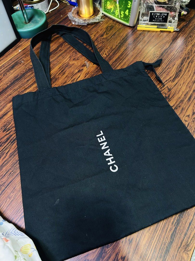 Black Chanel Canvas Tote Bag (Category: Tote Bags) located in Manila. Submitted by starbalesukandjapansurplus (Listing ID 1465960248, Image 3). Description: - Color & Material: Black canvas with shoulder straps - Design: White vertical Chanel logo on the front - Style: Simple, everyday carryall - Condition: Some wear on the fabric and minor glue residue near the strap attachment (see close-up photo).