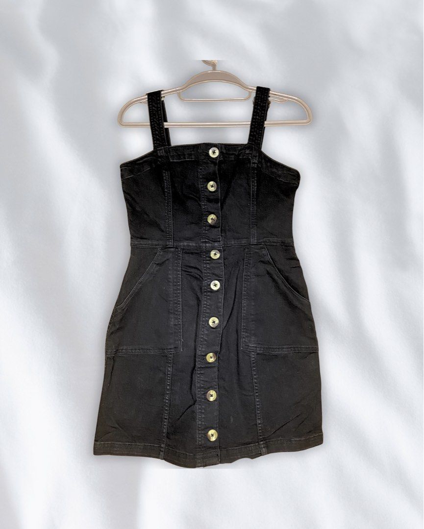 Black Denim Button-Up Pinafore Dress (Category: Dresses) located in Roxas City. Submitted by mariellaann_ (Listing ID 1466001480, Image 1). Description: - Color & Material: Black denim with a comfortable stretch - Design: Thick straps, tortoiseshell front buttons, and structured bodice with a flared hem - Features: Two large front patch pockets - Condition: Excellent, clean with no stains or fading - Styling: Great staple piece for layering over 