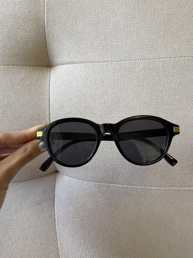 Black round sunglasses with gold accent (Category: Sunglasses & Eyewear) located in Pasig City. Submitted by miss_abuelita (Listing ID 1465975934, Image 2). Description: - Style: Classic round sunglasses - Color: Black with dark tinted lenses - Details: Elegant gold stripe hardware on both hinges - Inclusion: Free black drawstring soft pouch for safe storage - Condition: Brand new - Perfect for everyday wear and sunny days.