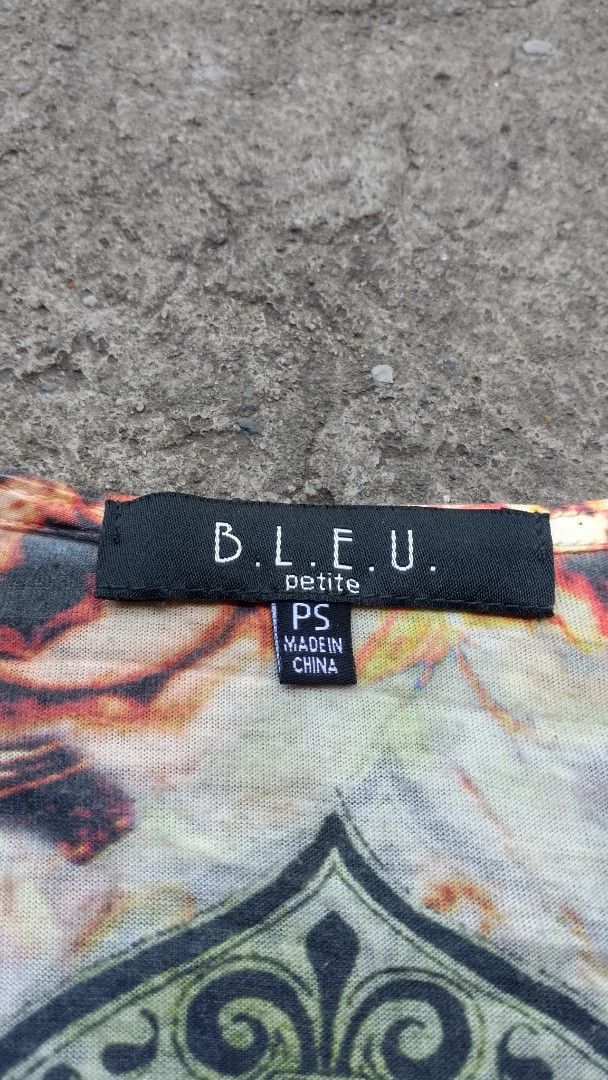 B.L.E.U. Petite Printed Blouse Size PS (Category: Blouses) located in Morong. Submitted by sanjuancla56319 (Listing ID 1465975308, Image 3). Description: - Brand: B.L.E.U. - Size: Petite Small (PS) - Material: 100% polyester - Design: Colorful vintage pattern with script writing and flared sleeves - Neckline: V-neck with embroidery, beadwork, and a central jewel brooch detail - Care Instructions: Hand wash cold, lay flat to dry - Origin: Made in 