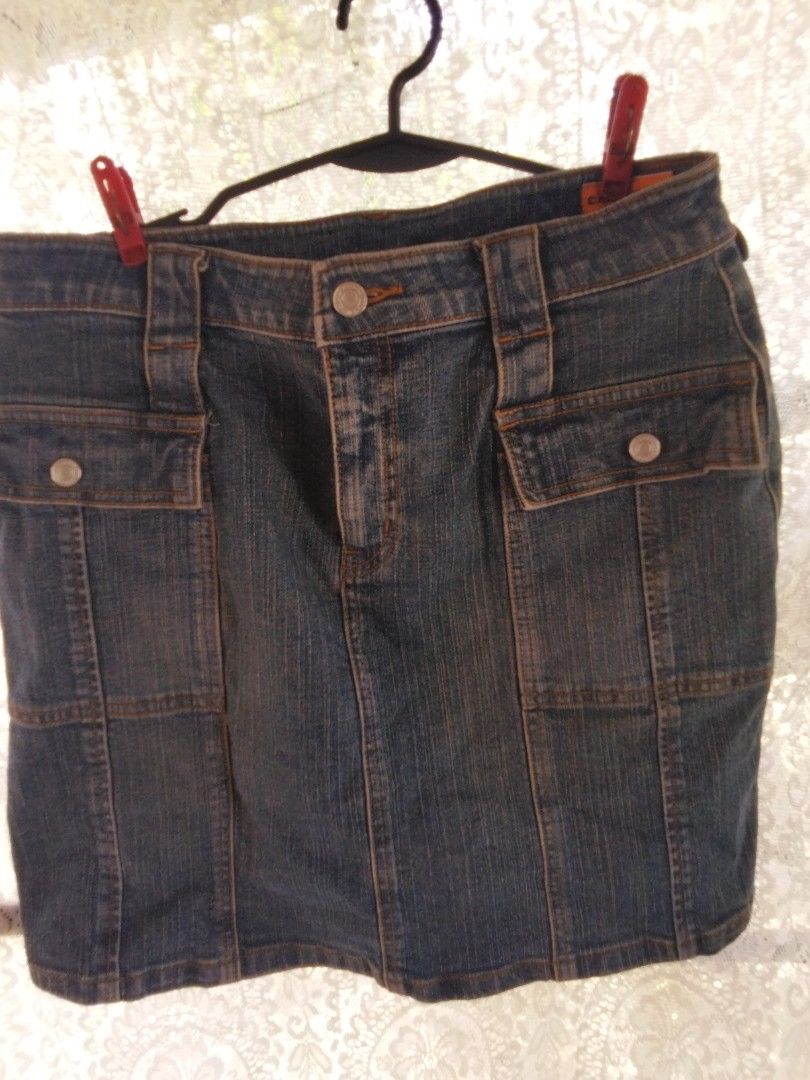 Blue denim cargo skirt with button pockets (Category: Skirts) located in Alaminos. Submitted by dangpreloved01 (Listing ID 1465969147, Image 1). Description: Mid-wash blue denim mini skirt with contrast stitching. Utility style cargo pockets on the front and back, secured with metal snap buttons. Sturdy belt loops and front button fly closure. Classic Y2K aesthetic, great for pairing with boots or sneakers. Clean hems and solid denim fabric..