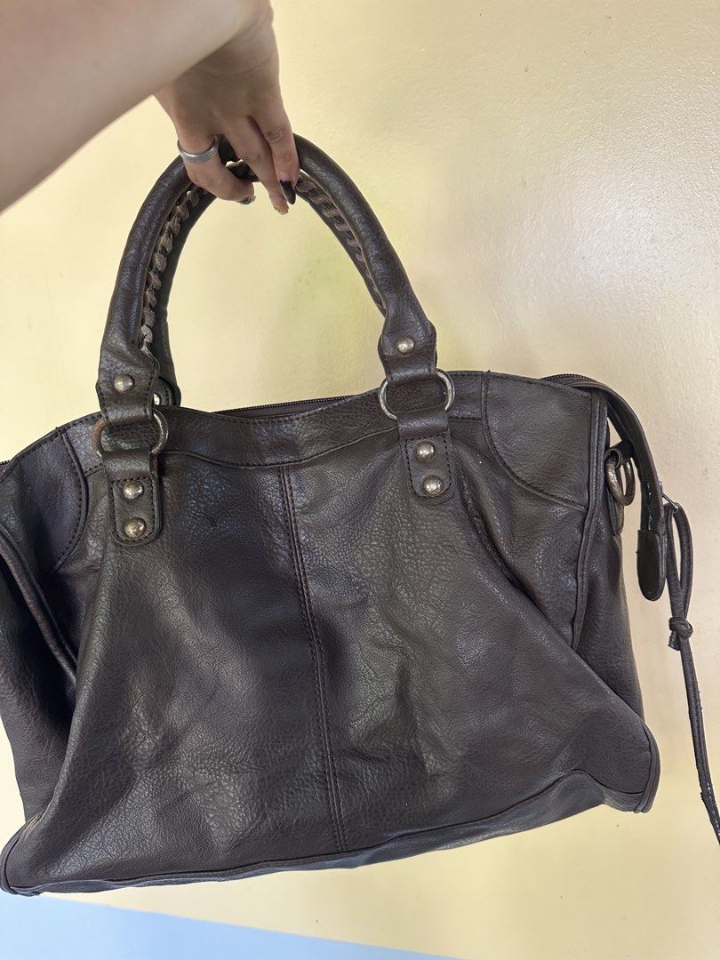 Brown Leather Handbag with Studs (Category: Luxury Bags & Wallets) located in Manila. Submitted by goldenhorse-dafc (Listing ID 1465961229, Image 3). Description: - - Color: Dark brown with silver-tone hardware - Material: Leather-like finish - Handles: Double top handles with braided details - Exterior: Front zip pocket and hanging tag - Interior: Lined with an extra zip compartment and slip pockets - Closure: Top zipper closure.