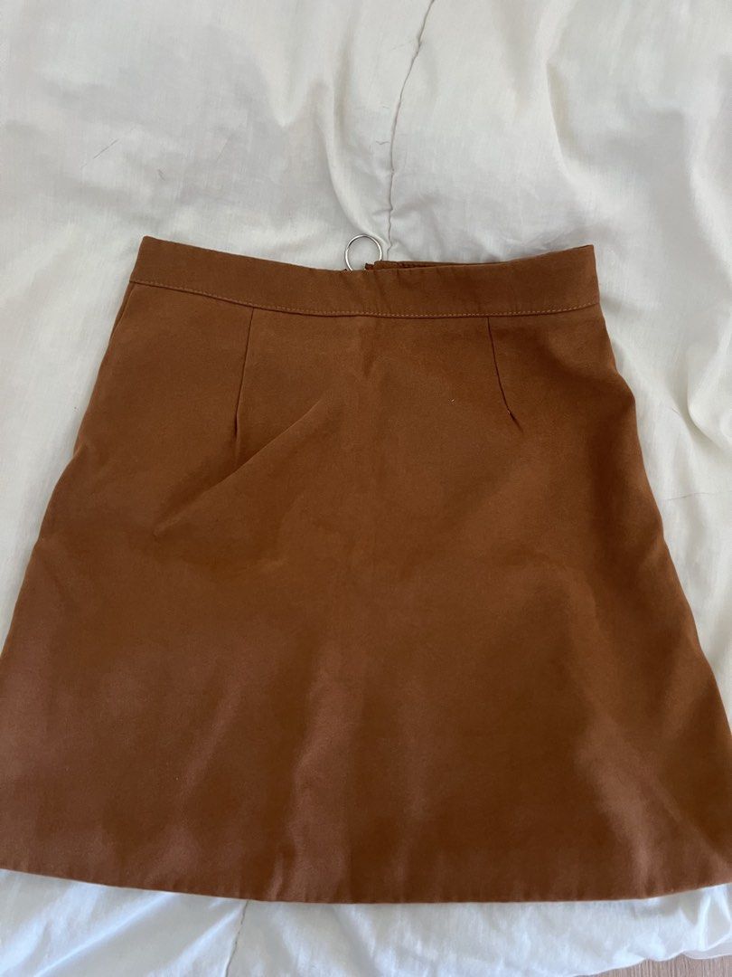 Brown Suede Mini Skirt with Front Zip and Pockets (Category: Skirts) located in Quezon City. Submitted by pattyyspreloved (Listing ID 1465964610, Image 2). Description: - Color: Rich earthy brown - Material: Smooth suede-texture fabric - Design: High-waist cut with darting on the back for a fitted shape - Details: Full-length silver front zipper with a trendy ring pull tab and two front patch pockets - Styling: Pairs perfectly with boots and knit