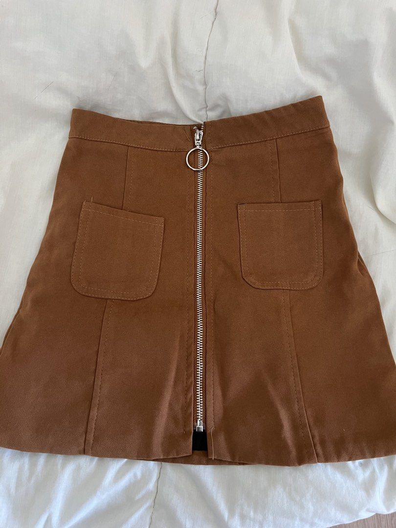 Brown Suede Mini Skirt with Front Zip and Pockets (Category: Skirts) located in Quezon City. Submitted by pattyyspreloved (Listing ID 1465964610, Image 1). Description: - Color: Rich earthy brown - Material: Smooth suede-texture fabric - Design: High-waist cut with darting on the back for a fitted shape - Details: Full-length silver front zipper with a trendy ring pull tab and two front patch pockets - Styling: Pairs perfectly with boots and knit