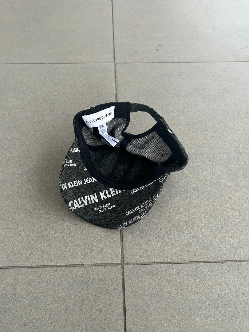 Calvin Klein Jeans All Over Logo Cap (Category: Caps & Hats) located in Pasig City. Submitted by paulclzdo (Listing ID 1466071905, Image 3). Description: - Brand: Calvin Klein Jeans - Material/Design: Dark denim fabric with all-over white logo print - Fit: Adjustable strap at the back with a secure metal clasp - Details: Interior branding tag stitched inside - Style: Great casual piece to easily throw on for daily wear.