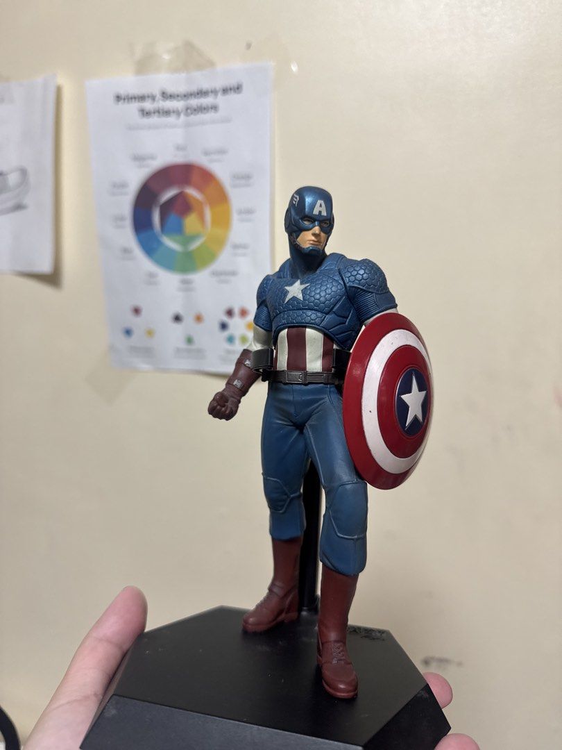 Captain America Figure with Shield and Base (Category: Figurines & Statues) located in Manila. Submitted by quintessesommerset (Listing ID 1465964066, Image 1). Description: - Figure: Captain America in his classic suit with detailed chest, shoulder texturing, blue trousers, and brown boots - Accessory: Iconic red, white, and blue star shield - Display: Includes a sturdy black hexagonal stand with a back support pillar - Condition: Stands upright