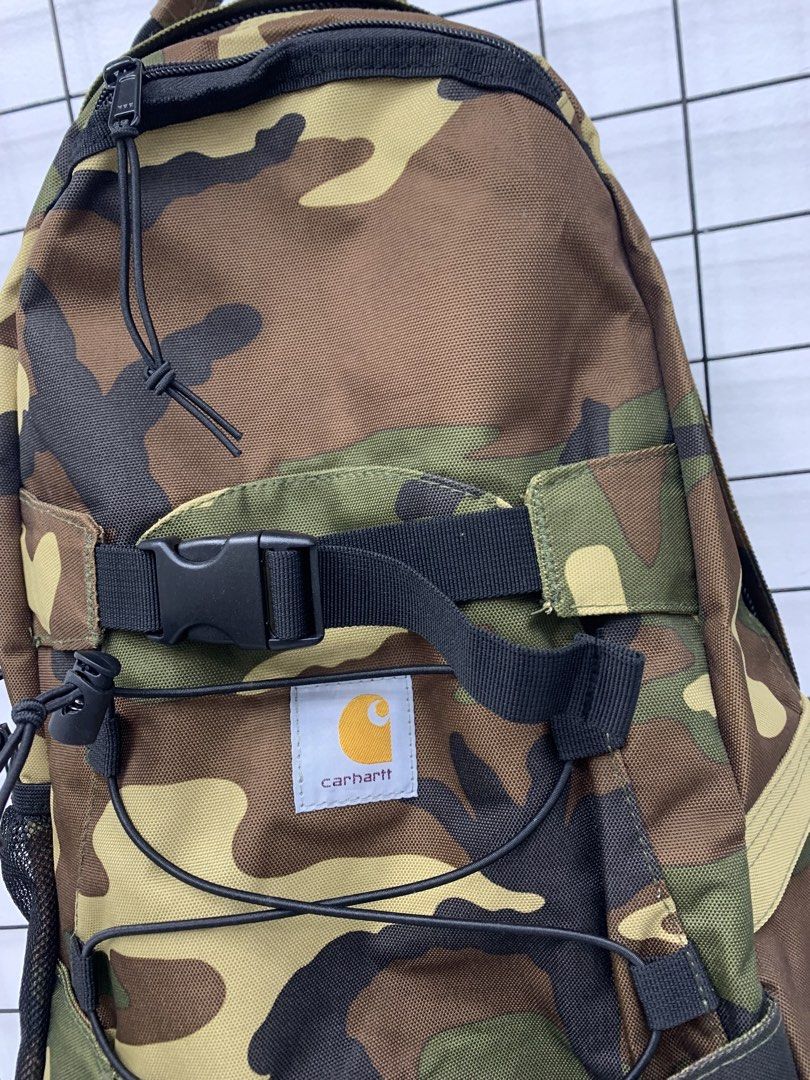 Carhartt Camouflage Backpack with Bungee Cords (Category: Backpacks) located in Cavite. Submitted by jeromeaba95864 (Listing ID 1466108579, Image 2). Description: - Brand: Carhartt - Pattern: Classic woodland camo - Material: Heavy-duty canvas built for durability - Storage: Spacious main compartment for daily carry, school, or travel - Exterior: Front dual buckle straps, elastic bungee cords, and dual mesh side pockets - Hardware: Smooth YKK zip