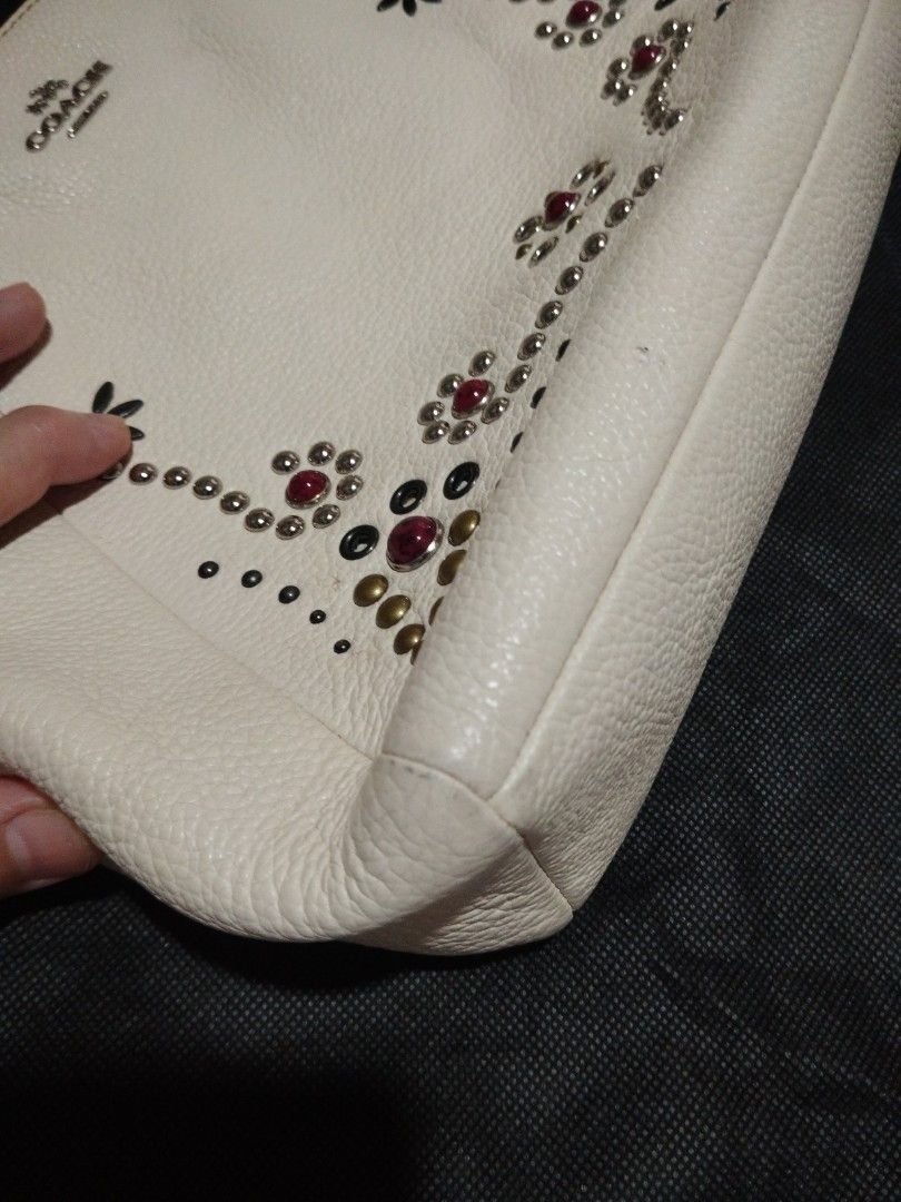 Coach Leather Studded Handbag with Strap (Category: Cross-body Bags) located in Manila. Submitted by lene48 (Listing ID 1466073254, Image 3). Description: - Brand: Coach - Material: Genuine white pebble leather - Design: Colorful stud embellishments and floral detailing on the front - Hardware: Silver-tone with matching Coach hangtag - Straps: Double top handles and adjustable, detachable long strap for crossbody wear - Interior: Brown fabric lin