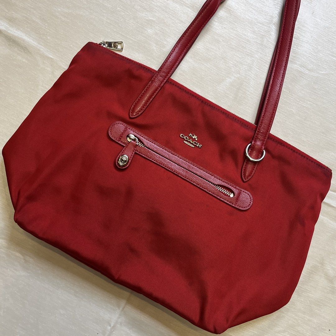 Coach Sawyer Red Nylon Tote Bag (Category: Tote Bags) located in Dasmarinas. Submitted by minx203 (Listing ID 1466101157, Image 2). Description: - Brand: Coach - Material: Durable bright red nylon with leather straps and trim - Closure: Secure top zip closure - Exterior: Front zippered pocket with twist-lock accent - Interior: Spacious red-lined fabric with an extra zip pocket and slip pockets - Condition: Shows minor discoloration near the top z