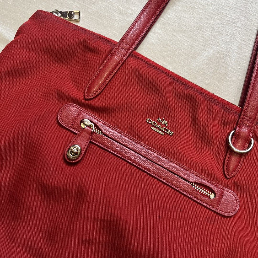 Coach Sawyer Red Nylon Tote Bag (Category: Tote Bags) located in Dasmarinas. Submitted by minx203 (Listing ID 1466101157, Image 3). Description: - Brand: Coach - Material: Durable bright red nylon with leather straps and trim - Closure: Secure top zip closure - Exterior: Front zippered pocket with twist-lock accent - Interior: Spacious red-lined fabric with an extra zip pocket and slip pockets - Condition: Shows minor discoloration near the top z