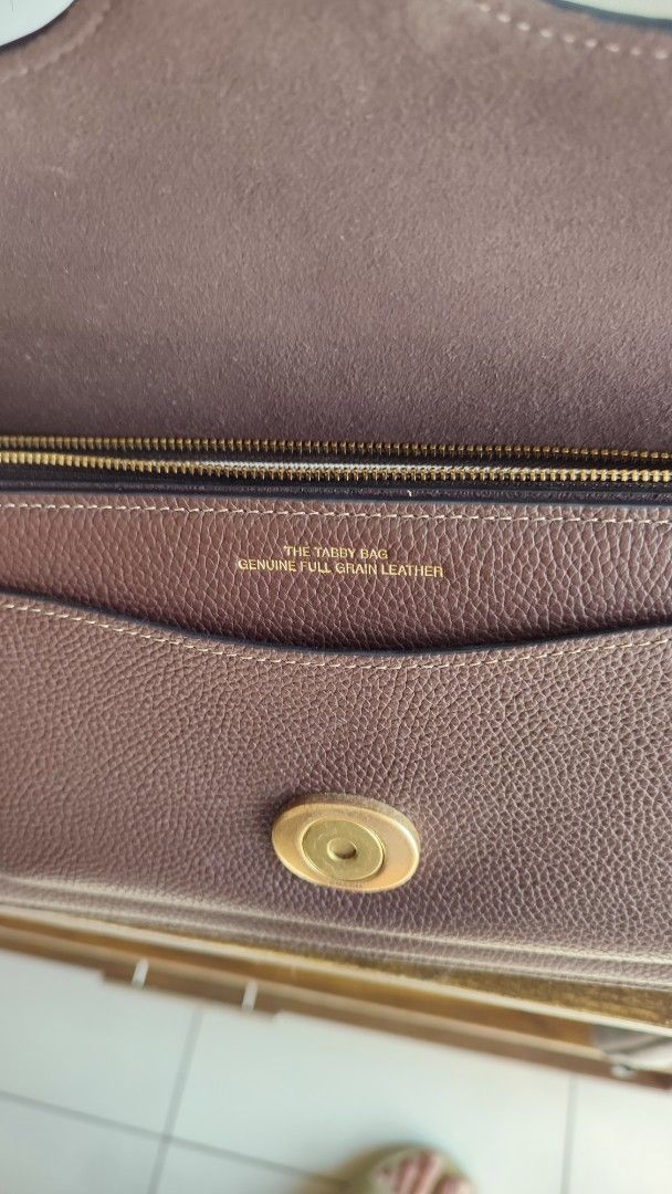 Coach Tabby Shoulder Bag Brown Leather (Category: Luxury Bags & Wallets) located in Manila. Submitted by trishcaj (Listing ID 1465959185, Image 2). Description: - Authentic Coach tabby 26 shoulder bag in dark brown pebbled leather - Antique brass Signature C hardware on the front flap - Structured accordion-style design with 3 internal compartments and a zippered pocket - Clean interior lining featuring the embossed gold logo stamp - Versatile st