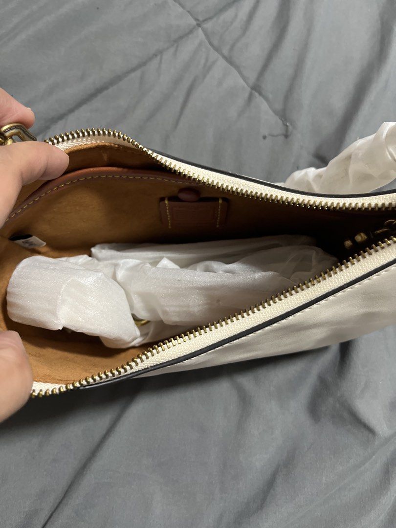 Coach White Leather Shoulder Bag (Category: Cross-body Bags) located in Pasig City. Submitted by melaiski28 (Listing ID 1465976923, Image 2). Description: - Brand: Coach - Material: Genuine glovetanned leather in white - Hardware: Gold-tone with Coach detailing - Straps: Includes a chunky gold chain strap and a detachable white leather strap (both still in protective packaging) - Interior: Brown lining with a slip pocket and leather patch - Desig