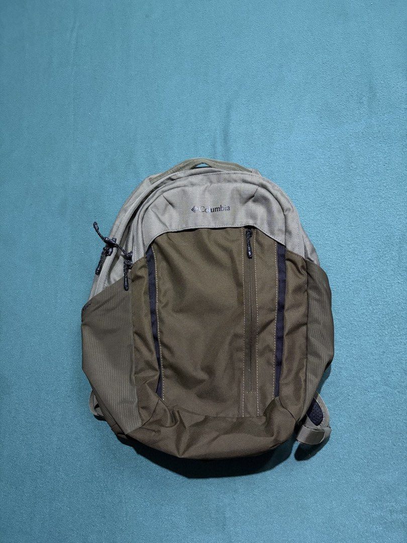 Columbia Green and Grey Backpack (Category: Backpacks) located in Guihulngan. Submitted by fbthriftgoodsniace (Listing ID 1465979826, Image 1). Description: - Brand: Columbia - Colorway: Olive green and grey - Dimensions: Approx. 18" tall x 15" wide - Pockets: Front vertical zipper pocket and side mesh water bottle holders - Comfort & Fit: Padded shoulder straps with built-in sternum clip and sturdy top handle - Condition: Clean fabric with minim