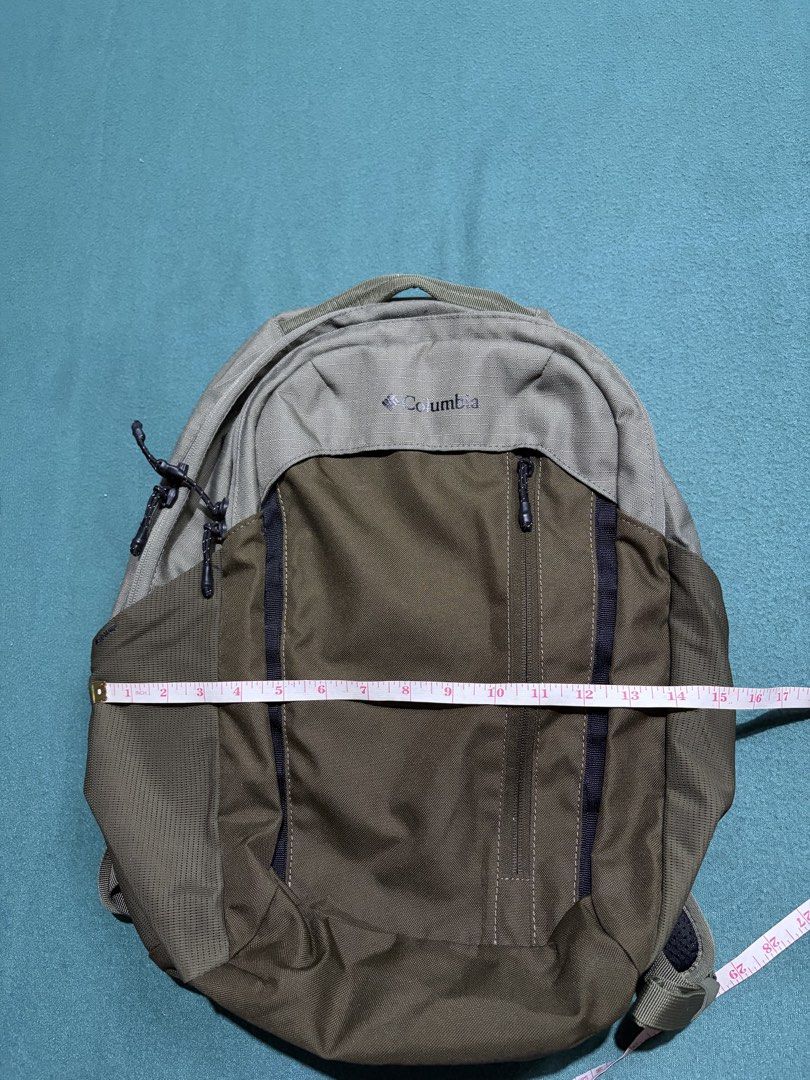 Columbia Green and Grey Backpack (Category: Backpacks) located in Guihulngan. Submitted by fbthriftgoodsniace (Listing ID 1465979826, Image 3). Description: - Brand: Columbia - Colorway: Olive green and grey - Dimensions: Approx. 18" tall x 15" wide - Pockets: Front vertical zipper pocket and side mesh water bottle holders - Comfort & Fit: Padded shoulder straps with built-in sternum clip and sturdy top handle - Condition: Clean fabric with minim