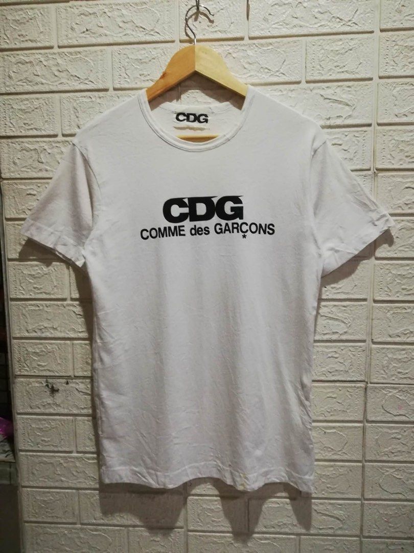 COMME des GARÇONS CDG White T-Shirt (Category: Shirts) located in Rizal. Submitted by tiangarcia02 (Listing ID 1466109451, Image 1). Description: - Brand: Comme des Garçons (CDG) - Color: White with black chest graphic - Material: 100% Cotton, Made in Japan - Style: Classic crew neck, short sleeves (Model: AZ-T026) - Condition: Clean, basic streetwear piece - Care: Hand wash only.
