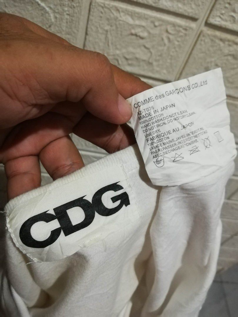 COMME des GARÇONS CDG White T-Shirt (Category: Shirts) located in Rizal. Submitted by tiangarcia02 (Listing ID 1466109451, Image 2). Description: - Brand: Comme des Garçons (CDG) - Color: White with black chest graphic - Material: 100% Cotton, Made in Japan - Style: Classic crew neck, short sleeves (Model: AZ-T026) - Condition: Clean, basic streetwear piece - Care: Hand wash only.