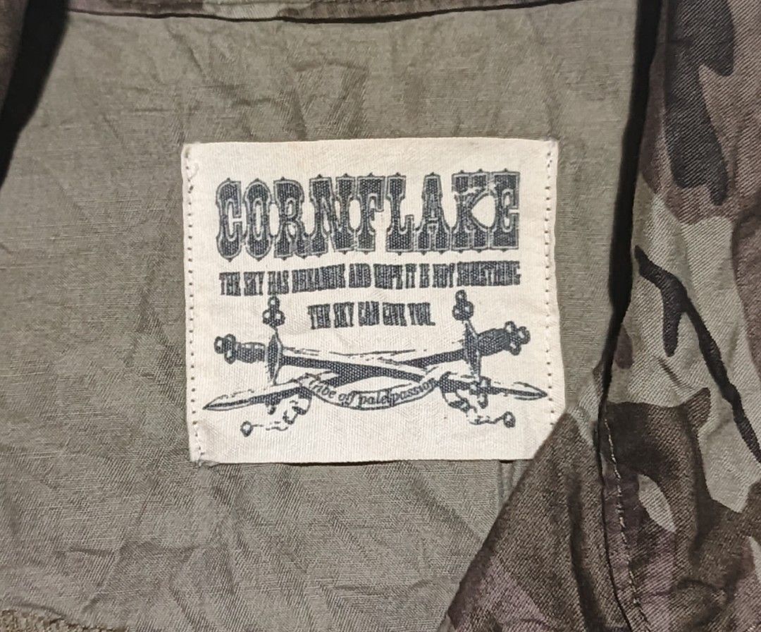 Cornflake Camouflage Zip Up (Category: Coats, Jackets and Outerwear) located in Calabanga. Submitted by bekneegear (Listing ID 1466123159, Image 3). Description: - Style: Rugged military-inspired utility camo jacket - Color: Green and brown cornflake camo tones - Design: Short sleeves, front zipper closure, and high collar neckline - Pockets & Details: Dual chest pockets with zipper accents, decorative metal pull tabs, and antique bronze buttons 