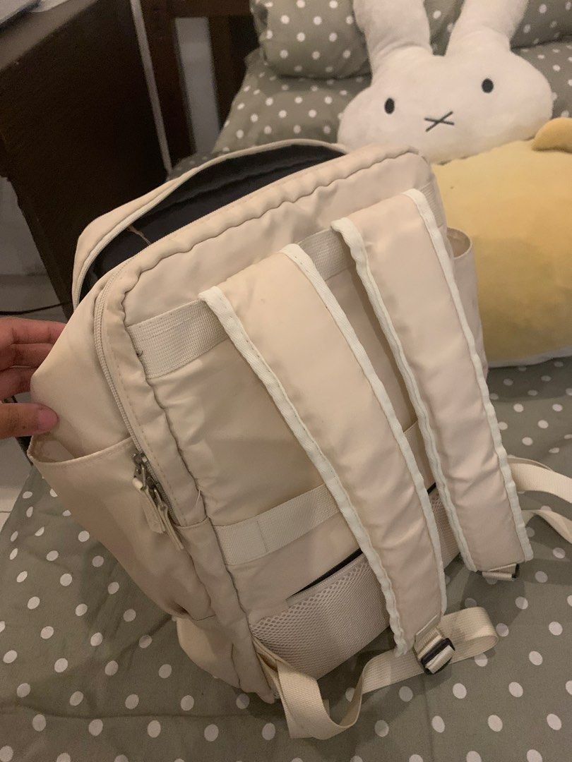 Cream beige multi-pocket travel backpack (Category: Backpacks) located in Manila. Submitted by pureforest_68db5f (Listing ID 1466074251, Image 2). Description: - Color: Cream beige with stylish front metal grommets - Storage: Multiple zippered compartments and convenient side pockets - Interior: Black lining with a mesh pocket divider - Comfort: Adjustable shoulder straps with breathable mesh backing - Condition: Shows visible scuff marks and dir