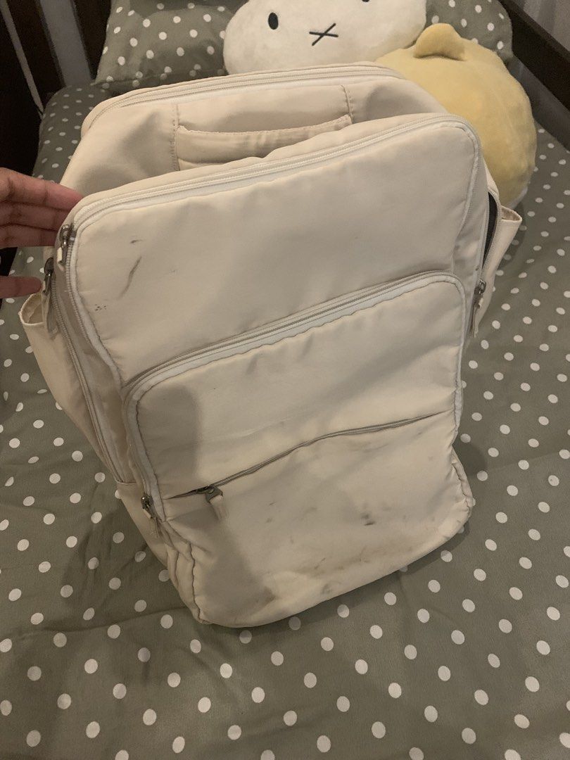 Cream beige multi-pocket travel backpack (Category: Backpacks) located in Manila. Submitted by pureforest_68db5f (Listing ID 1466074251, Image 1). Description: - Color: Cream beige with stylish front metal grommets - Storage: Multiple zippered compartments and convenient side pockets - Interior: Black lining with a mesh pocket divider - Comfort: Adjustable shoulder straps with breathable mesh backing - Condition: Shows visible scuff marks and dir