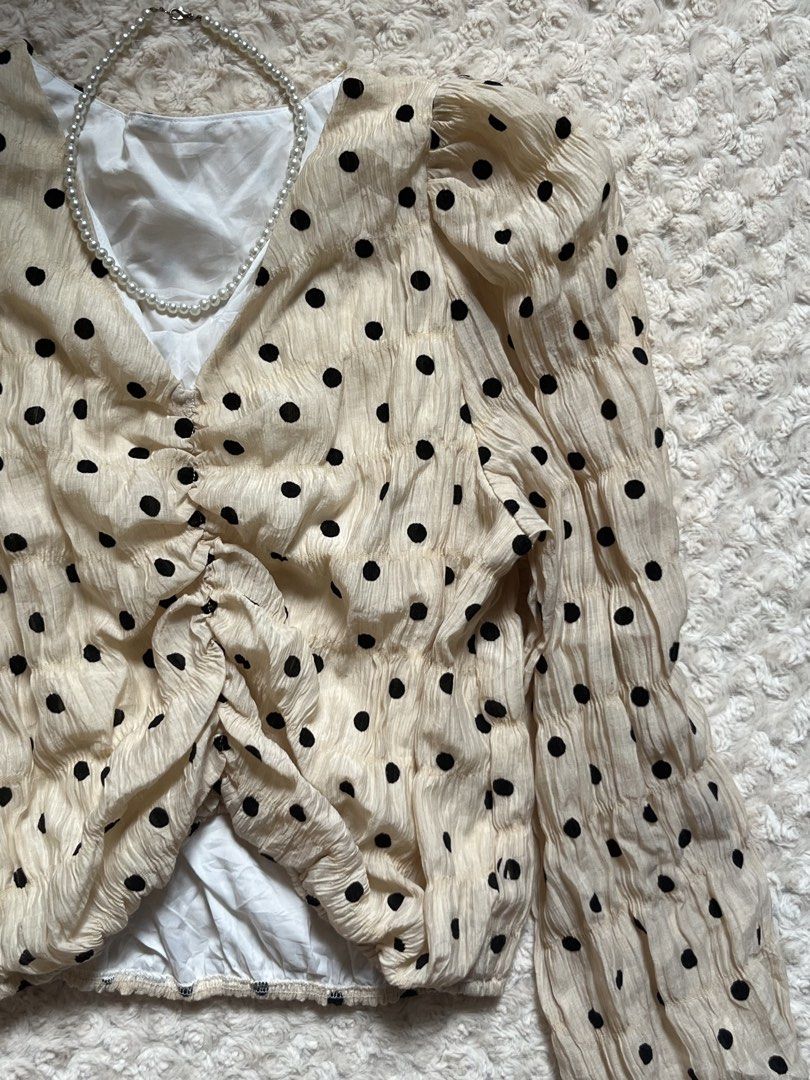 Cream Polka Dot Puff Sleeve Blouse (Category: Blouses) located in Mandaluyong City. Submitted by namislounge (Listing ID 1466042657, Image 2). Description: Selling to declutter! - Color/Pattern: Cream with black polka dots - Design: V-neckline with front center ruching - Sleeves: Long puff sleeves with elastic hem - Fabric: Lightweight, textured, and very breathable - Styling: Perfect to pair with jeans or skirts for a chic look - Best fits small