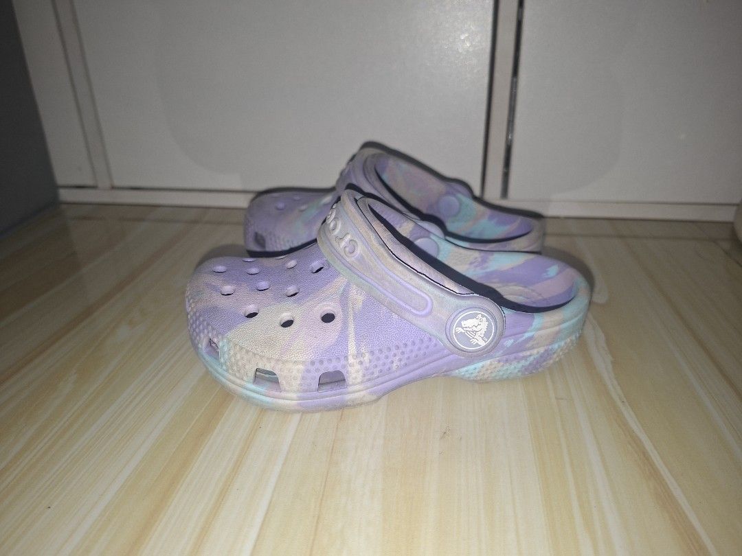 Crocs Classic Clog Purple Multi Marble Kids Size C7 (Category: Babies & Kids Fashion) located in Marilao. Submitted by rdnl28 (Listing ID 1466041915, Image 1). Description: - Size: Kids C7 - Color/Design: Purple and blue marbled pattern - Style: Slip-on clog sandals with pivoting heel straps - Features: Ventilation ports on the upper toe area for breathability - Condition: Soles show normal wear from everyday use - Perfect fun and colorful footwe