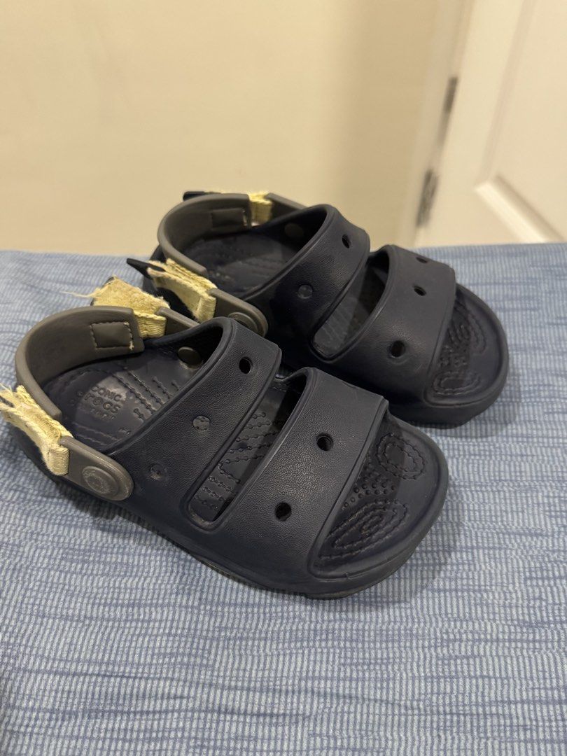 Crocs Kids Navy Blue Sandals (Category: Babies & Kids Fashion) located in San Fernando. Submitted by jelajoybasco (Listing ID 1466099059, Image 1). Description: - Color: Navy blue - Design: Double strap with adjustable fabric heel straps - Material: Lightweight foam with textured footbed for extra grip - Style: Easy slip-on - Condition: Ready for casual wear, with minor fraying on the fabric strap edges - Size C 11.