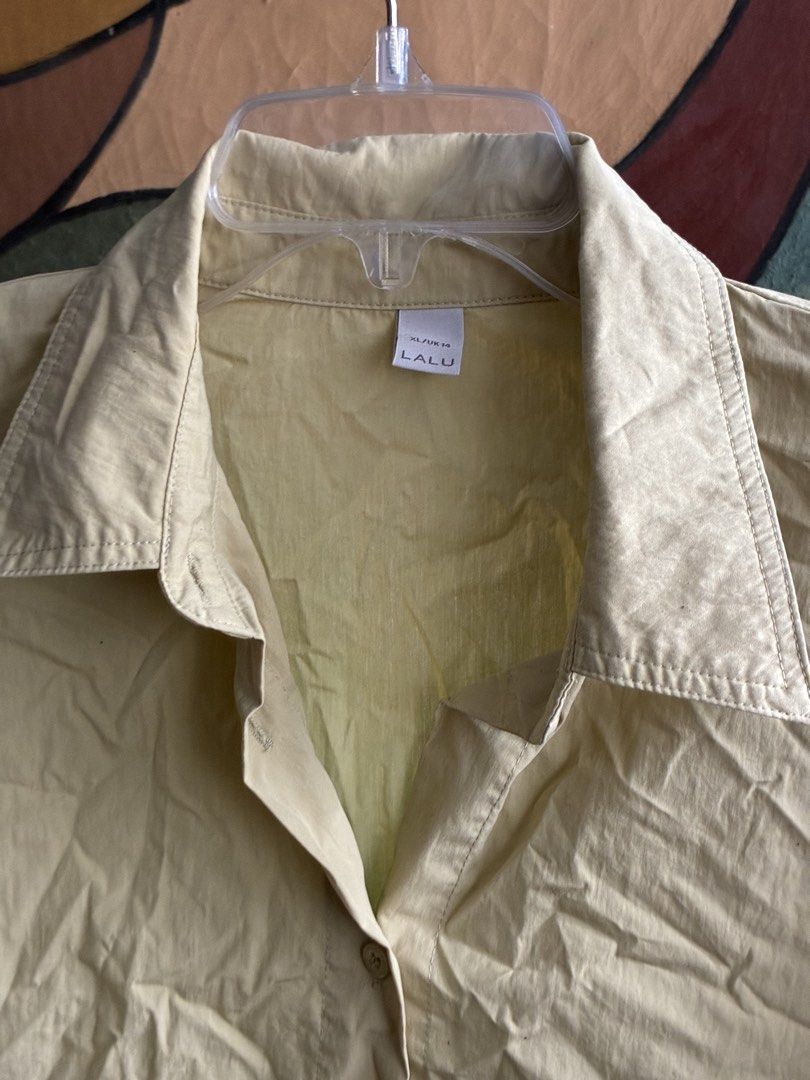 Cropped Khaki Button-Up Shirt XL (Category: Blouses) located in Pasig City. Submitted by alvinthedecluttererist (Listing ID 1466020490, Image 2). Description: - Brand: Lalu - Color: Light Yellow, Khaki -Width: 44cm, Length: 53cm - Size: XL / UK 14 - Fit: Relaxed and lightweight - Features: Short sleeves with folded cuff, collared neckline, front button closure, and elastic gathered hem - Condition: Great for casual warm-weather wear.
