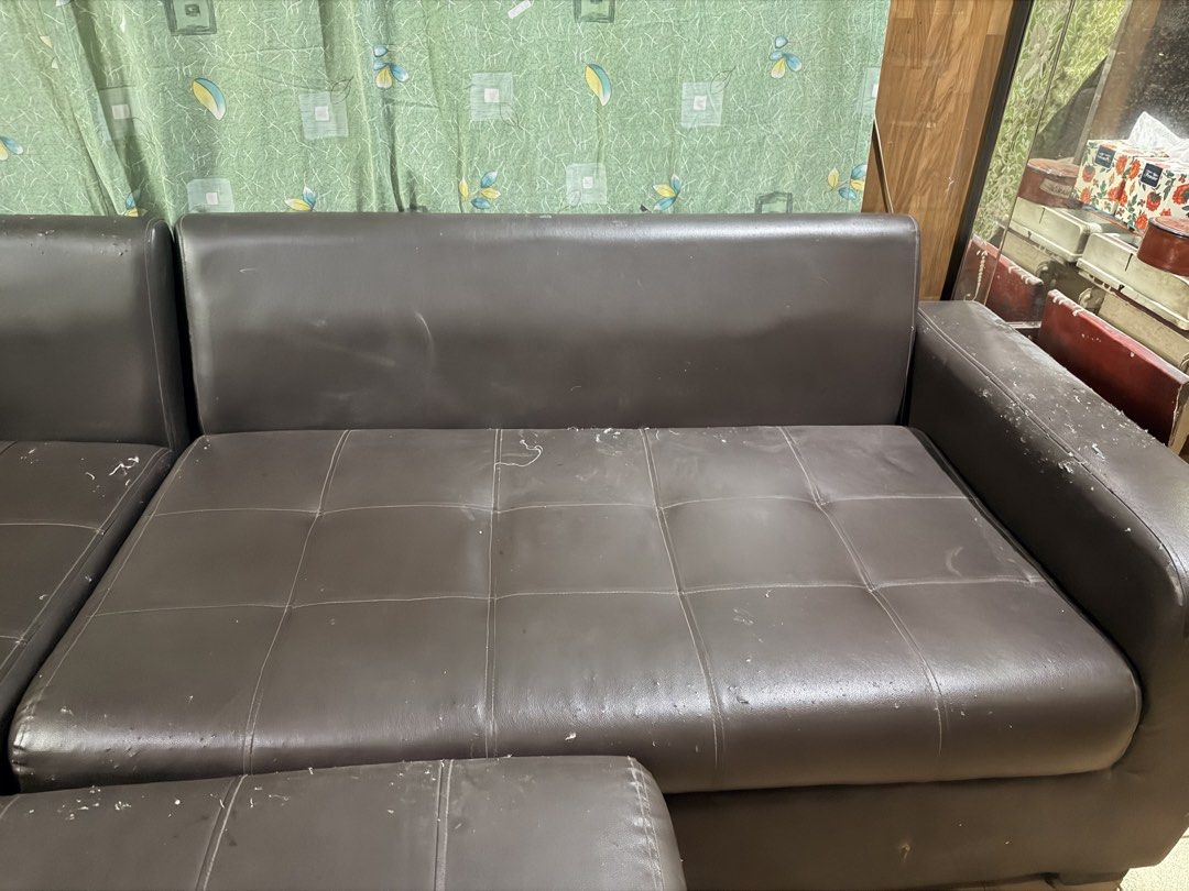 Dark brown leather sectional sofa with matching ottoman (Category: Sofas) located in Quezon City. Submitted by BAYMAX72 (Listing ID 1465975575, Image 3). Description: - Dark brown faux leather sectional sofa with matching footstool ottoman - Elegant tufted cushioning on seats and ottoman - Solid and sturdy internal structure - Noticeable wear and tear from pet scratches on arms, top edges, and seating surfaces - Fully functional and ready for use