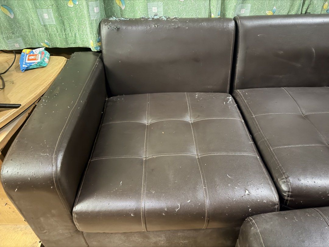 Dark brown leather sectional sofa with matching ottoman (Category: Sofas) located in Quezon City. Submitted by BAYMAX72 (Listing ID 1465975575, Image 2). Description: - Dark brown faux leather sectional sofa with matching footstool ottoman - Elegant tufted cushioning on seats and ottoman - Solid and sturdy internal structure - Noticeable wear and tear from pet scratches on arms, top edges, and seating surfaces - Fully functional and ready for use