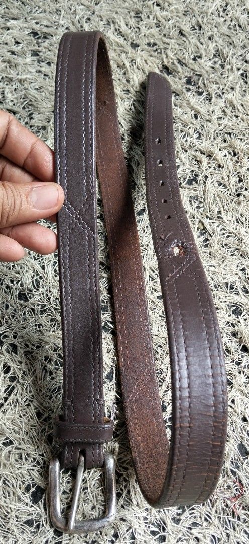 Dark brown PURE SOLID GENUINE leather belt with silver tone buckle (Category: Belts) located in Paranaque City. Submitted by michael-08 (Listing ID 1466038640, Image 3). Description: - Color: Dark brown with a textured finish - Material: Genuine leather strap with silver-tone metal buckle - Details: Stylish double row stitching - Fit: Multiple sizing holes for an adjustable fit - Style: Classic casual design, ideal for everyday wear PURE SOLID GE