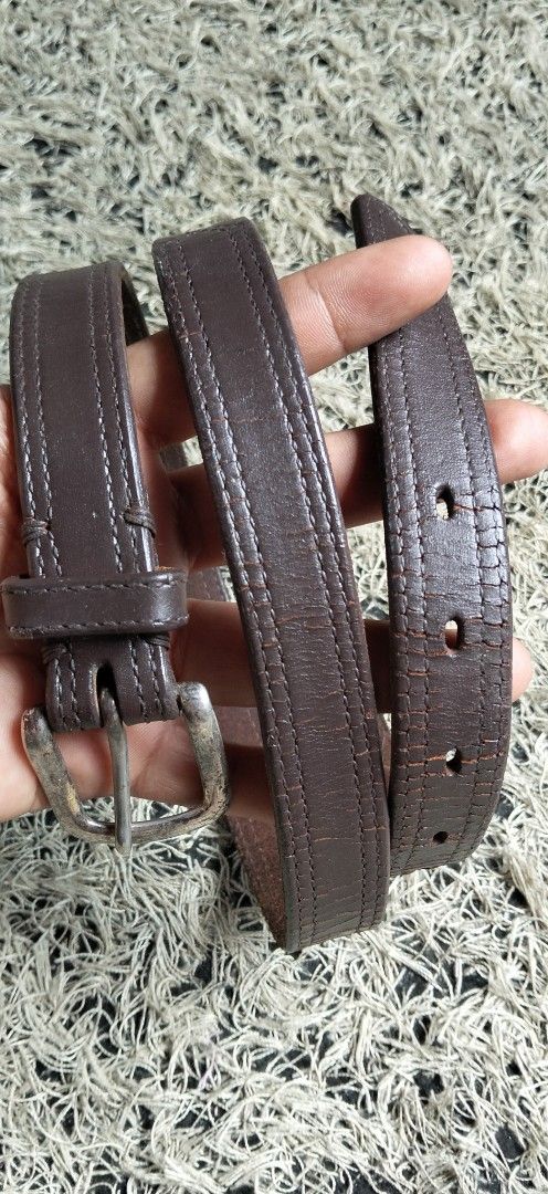 Dark brown PURE SOLID GENUINE leather belt with silver tone buckle (Category: Belts) located in Paranaque City. Submitted by michael-08 (Listing ID 1466038640, Image 1). Description: - Color: Dark brown with a textured finish - Material: Genuine leather strap with silver-tone metal buckle - Details: Stylish double row stitching - Fit: Multiple sizing holes for an adjustable fit - Style: Classic casual design, ideal for everyday wear PURE SOLID GE