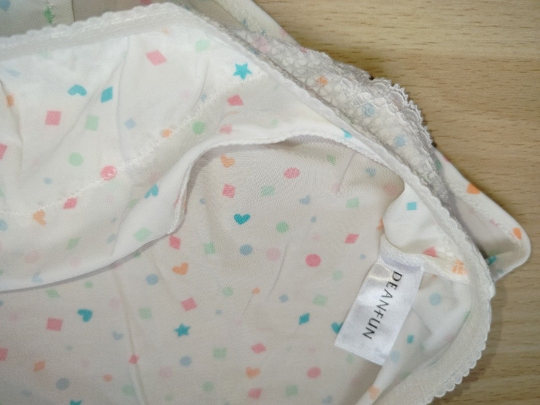 DEAN-FUN White Patterned Panties with Lace Detail (Category: Undergarments & Loungewear) located in Rizal. Submitted by etcthings (Listing ID 1466153589, Image 3). Description: White panties with colorful geometric shapes like hearts, stars, squares, and circles printed all over. Soft white lace panel across the top band. Small white bow centered at the front waistband. Smooth fabric with clean white stitching throughout. Tag reads DEAN-FUN on th