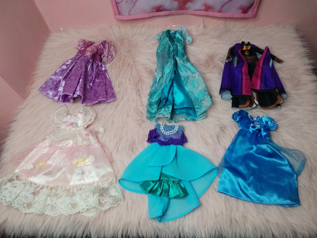 Disney Princess Doll Dresses (Category: Kids Toys) located in Paombong. Submitted by eandj.shop (Listing ID 1466053046, Image 2). Description: 🎀 Set of 6 stunning doll dresses 🎀 Variety of styles: Purple sparkly gown, light blue glitter ice dress, purple/black cape outfit, pink satin dress with lace, turquoise high-low dress with pearls, and bright blue satin dress 🎀 Perfect for playtime, dress-up, and expanding your doll's wardrobe.