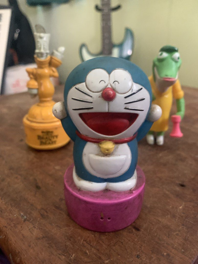 Doraemon Figure Toy on Pink Stand (Category: Figurines & Statues) located in Makati City. Submitted by emenem.m (Listing ID 1465986420, Image 1). Description: - Item: Classic Doraemon Collectible Figurine - Design: Standing happily on a pink circular base with iconic blue/white body, red collar, and yellow bell - Condition: Pre-owned with minor dirt marks and scuffs from display - Perfect for: Doraemon fans and anime collectors looking to add a n