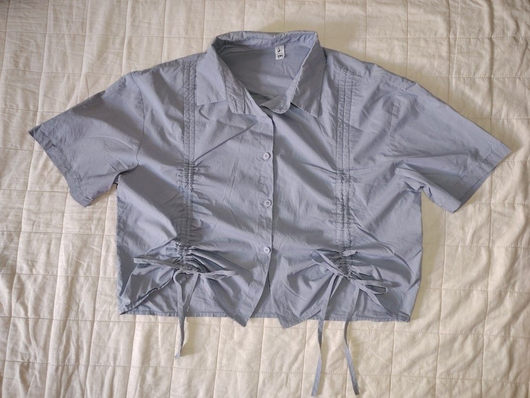 Dust Blue Ruched Drawstring Short Sleeve Button-Down Crop Shirt (Category: Blouses) located in Tarlac. Submitted by your_finds (Listing ID 1466008946, Image 1). Description: Description: - Large ang size - Dusty blue ang color - Cropped collared button-down shirt - Adjustable front drawstrings Condition: 9/10 / Very good condition Medida size (inch) Bust: 40 Length: 18.