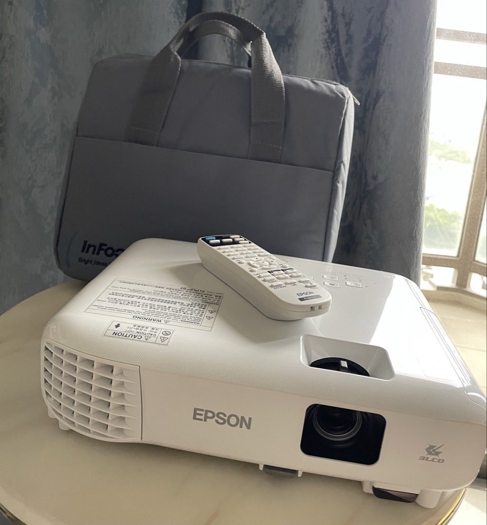 Epson EB-E01 Projector (Category: Projectors) located in Manila. Submitted by little_amy (Listing ID 1466064633, Image 2). Description: - Model: Epson EB-E01 Projector (White housing) - Connectivity: Built-in HDMI port support - Controls: Standard top panel buttons (Power, Home, Menu, Source Search) - Features: Lens focus slider near front corner for easy adjustments - Lamp: Uses ELPLP97 replacement lamp model - Setup: Standard desktop design, pe