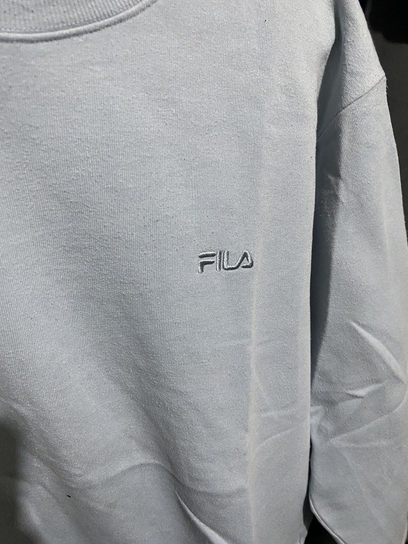 Fila Light Blue Sweatshirt Size L (Category: Coats, Jackets and Outerwear) located in Imus. Submitted by frootiloots4103 (Listing ID 1466033683, Image 2). Description: - Brand: Fila - Color: Light Blue - Size: L (Tag attached at collar with branded neck label) 23x25 - Design: Crew neck with stylish striped inner collar tape - Details: Embroidered Fila logo on the chest and small woven Fila tag near the bottom hem.