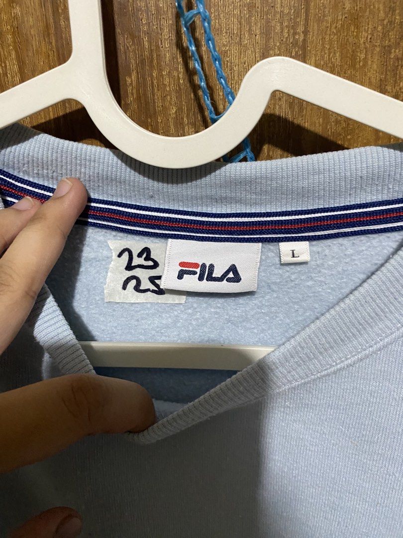 Fila Light Blue Sweatshirt Size L (Category: Coats, Jackets and Outerwear) located in Imus. Submitted by frootiloots4103 (Listing ID 1466033683, Image 3). Description: - Brand: Fila - Color: Light Blue - Size: L (Tag attached at collar with branded neck label) 23x25 - Design: Crew neck with stylish striped inner collar tape - Details: Embroidered Fila logo on the chest and small woven Fila tag near the bottom hem.